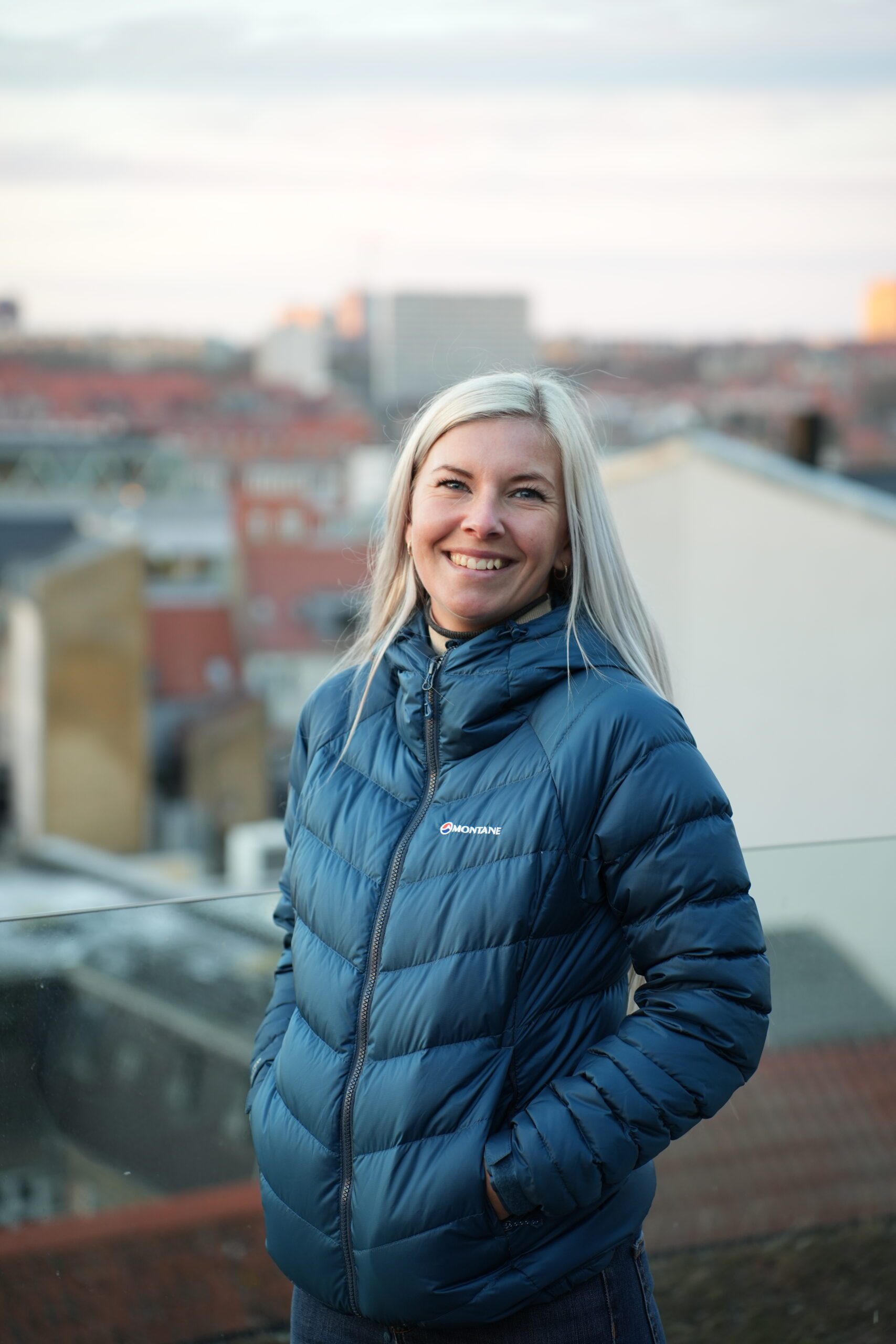 Portræt af smuk kvinde på toppen af Salling Rooftop i Aarhus, med udsigt over noget af Aarhus